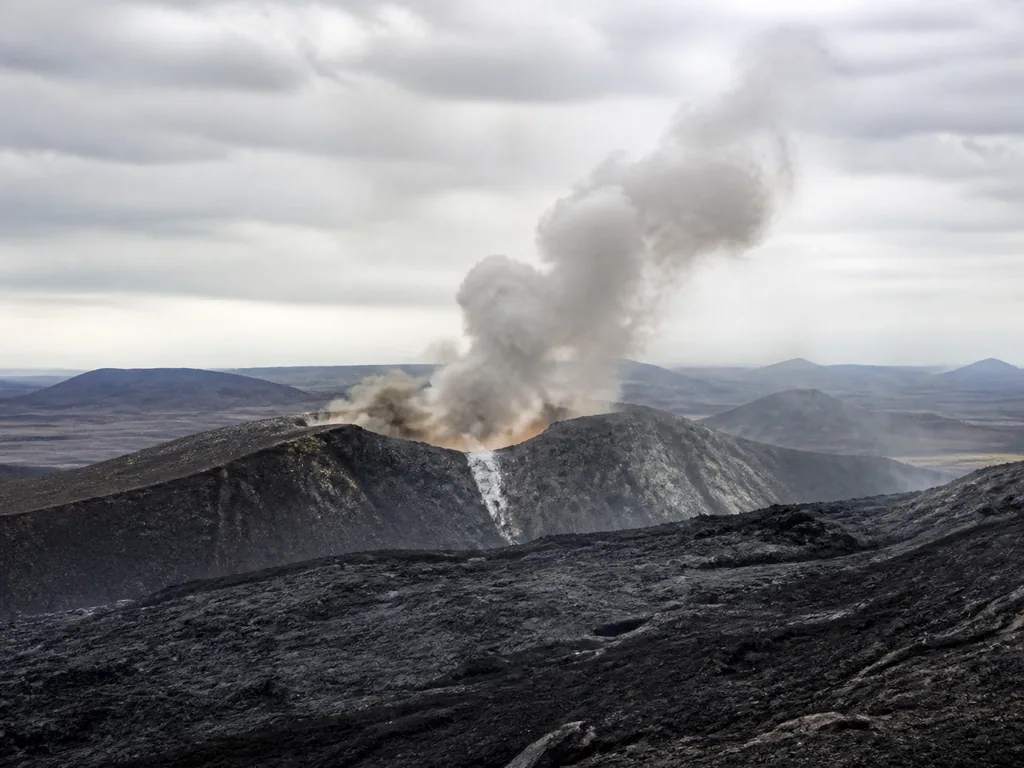 A volcano erupting above a dark landscape.